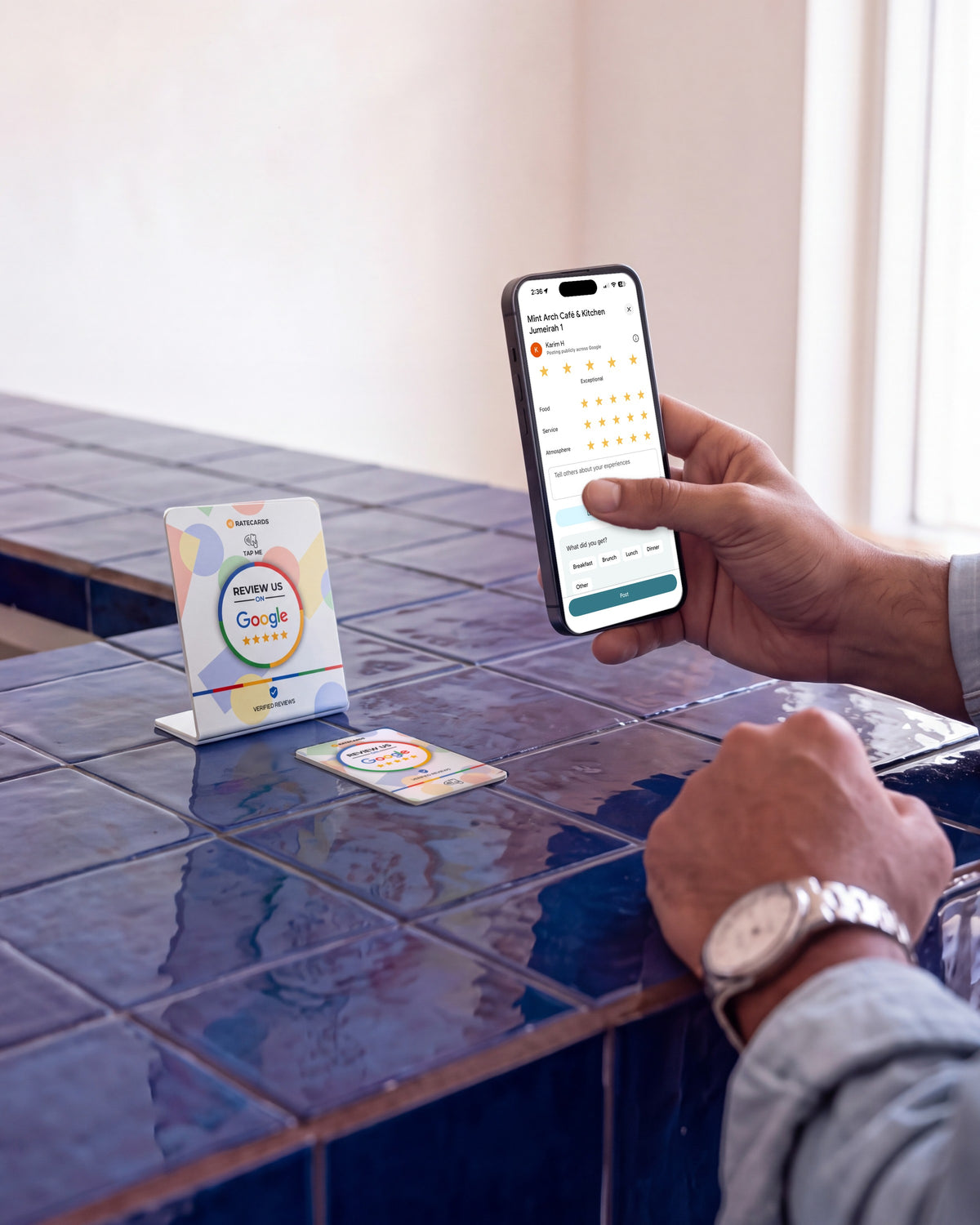 RATECARDS Google Review Card and Google Review Stand on a tiled café counter, phone showing the Google review screen